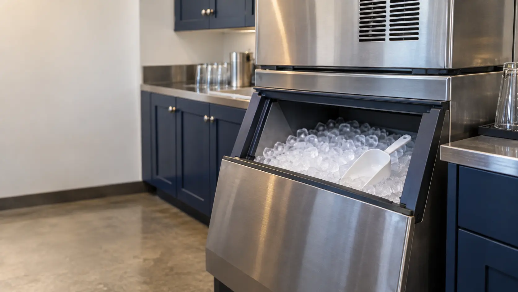 A restaurant back room with a modular ice machine on its bin and navy painted cabinets, seen close at the ice machine's bin door.