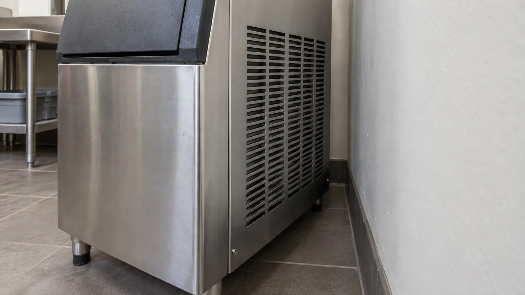 Close on the open space left beside the vents of an ice machine against a wall.